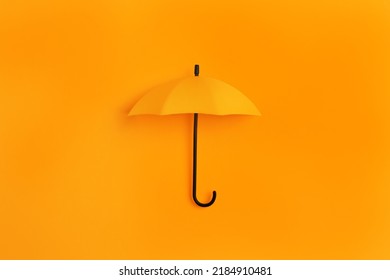 Bright toy umbrella on orange background, top view