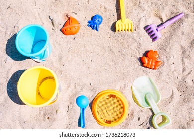 Bright Toys On Sand. Selection Of Beach Toys On White Sandy Beach. Top View Of Colourful Hildren's Toys To Play In Sand On Family Summer Vacation. Background With Empty Space For Text. Selective Focus