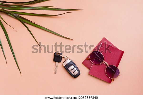 Bright\
travel flat lay with sunglasses, passports, palm leaves and car\
keys on a beige background. Car travel. Top\
view