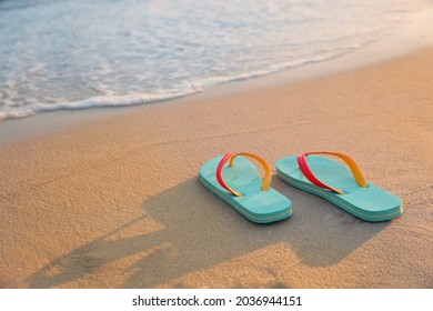 Bright turquoise beach slippers on sand near sea, space for text - Powered by Shutterstock