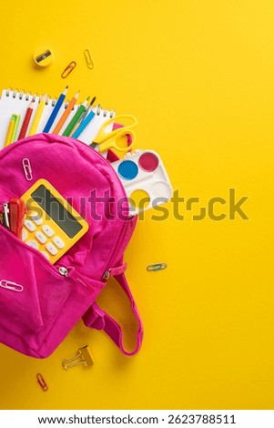 Bright vertical image of an open backpack filled with school supplies like pencils, watercolor, and a calculator