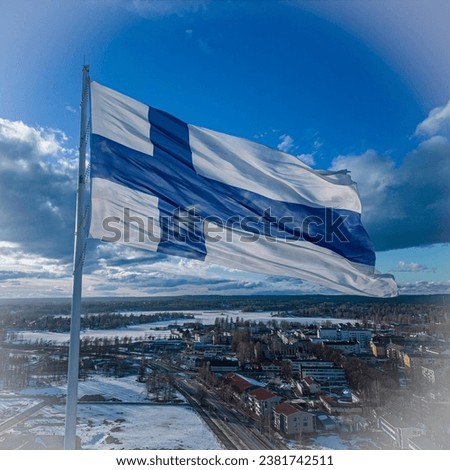 A bright and vibrant American flag blowing in the wind against a backdrop of a wintery cityscape under a brilliant blue sky