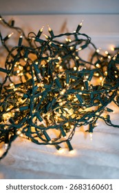 Bright warm string lights with green wires spread across a white fabric surface, ideal for holiday decor or festive ambiance.