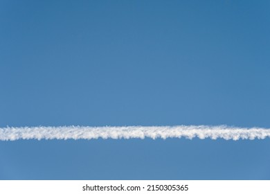 Bright White Contrail Cloud Against A Clear Blue Sky, As A Graphic Background
