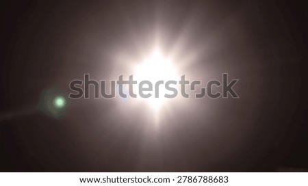 A bright white light source creates a starburst lens flare effect against a dark black background.