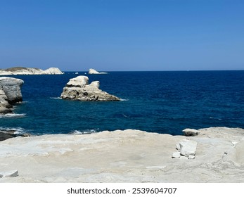 Bright white rock formations meet the deep blue sea, contrasting vividly under a clear sky. The rocky coastline is rugged and sunlit, while distant white cliffs add depth to this serene Mediterranean  - Powered by Shutterstock