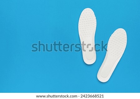 Bright white shoe insoles on a blue background. Shoe accessories.