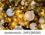 Bright white and silver ornamernts on Christmas tree against a background of bokeh of Christmas lights. New Year, Christmas background. Christmas tree, boxes with gifts,New year