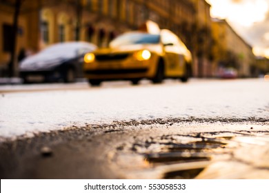 Bright winter sun in a big city, the taxi rides on the street. Close up view of a hatch at the level of the asphalt - Powered by Shutterstock