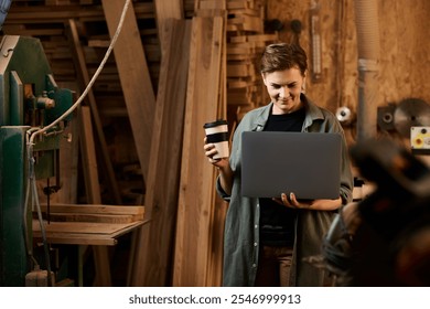 In a bright workshop, a female carpenter analyzes plans on her laptop while holding a coffee cup. - Powered by Shutterstock