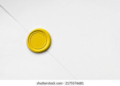 Bright yellow blank circular wax seal against white paper.