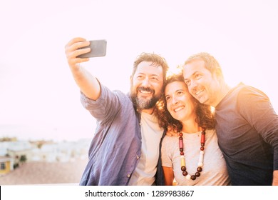 Bright Yellow Filter Group Of Caucasian 40 Years Old People Men And Woman Taking Selfie Picture With Smart Phone Device - Backlight And White Sky In Bnackground - Happy Leisure Activity Toncept