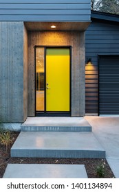A bright yellow front door being illuminated by a single porch light