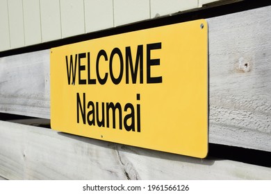 A Bright Yellow Sign With The English Word Welcome And The New Zealand Maori Word Naumai