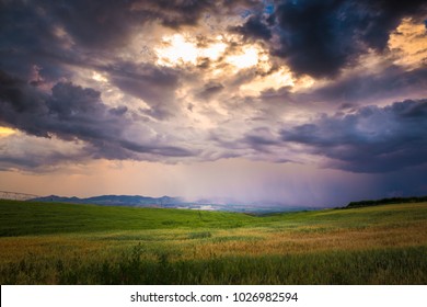 The bright yellow sun breaking through the dark stormy clouds during a colorful morning in beautiful Idaho farmland country. 