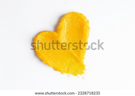 Bright yellow swatches of the mango body scrub.
Skincare cosmetic cream lotion swatch smear smudge on white color background. Scrub hygiene beauty product close up