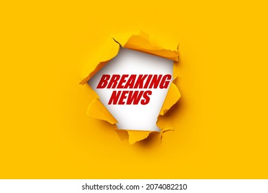 Bright yellow torn paper inside in a hole Breaking news on a white background  - Shutterstock ID 2074082210