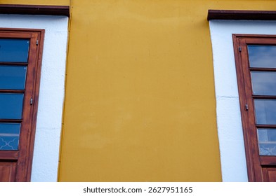 Bright yellow wall with symmetrical wooden windows and white accents, perfect for urban design or architectural backgrounds. - Powered by Shutterstock - Get 15% off with code: PIKWIZARD15