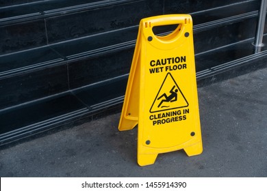 Bright Yellow Warning Janitorial Sign Of 'caution Wet Floor, Cleaning In Progress' At Front Of Wet Stairs To Warn Passersby For Safety.