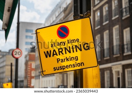 Bright yellow warning sign for a temporary parking suspension on a London city road