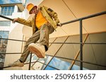 Bright youth style in clothes. Modern brunette guy poses in fashionable colorful loose clothes on the metal stairs of a skyscraper in a big city. New autumn fashion.