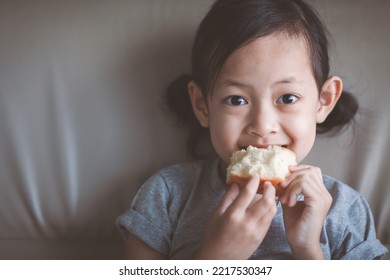 Bright-eyed Asian Girl Happily Eating Bread.Children Concept With Healthy Food.