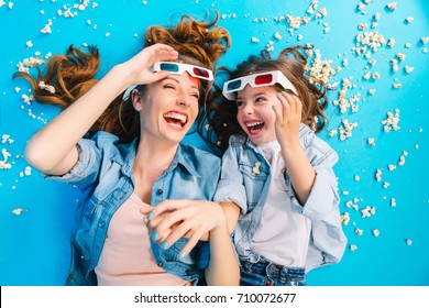 Brightful Stylish Image From Above Excited Mother And Daughter Laying On Blue Floor In Popcorn, Laughing  In 3D Glasses. Happy Family Time, Entertainment Pretty Mum With Kid, Expressing Happiness