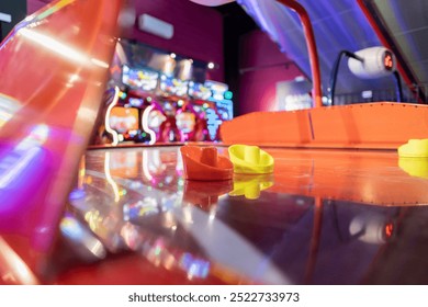 Brightly colored air hockey mallets on a reflective table in a vibrant arcade setting, blurred background. - Powered by Shutterstock