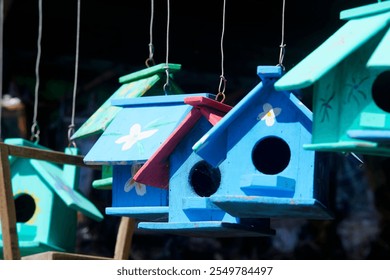 Brightly colored birdhouses hang delicately in a natural setting, showcasing vibrant hues of blue, green, and red. Perfect for capturing the essence of outdoor charm. - Powered by Shutterstock