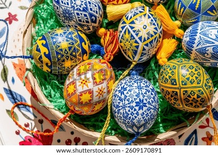 Brightly colored Easter eggs are artistically arranged in an Easter basket, showcasing traditional Ukrainian pysanky adorned with elaborate folk patterns.