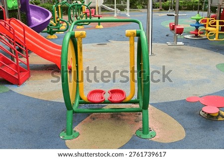A brightly colored exercise machine. To use it, stand on the platform and swing your legs forward and backward in public parks.