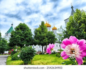 Brightly colored flowers bloom in a lush park with historic church domes in the background under a partly cloudy sky. - Powered by Shutterstock