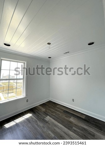 A brightly colored room that's been completely renovated with freshly painted walls, and ceiling along with brand new floors. The ceiling is ship lap and has a semi-gloss finish.