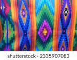 Brightly colored traditional fabric for sale at Otavalo market in Ecuador.  Vertical view