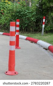 Brightly colored traffic cones and posts are placed along a road's edge to delineate boundaries and direct vehicles