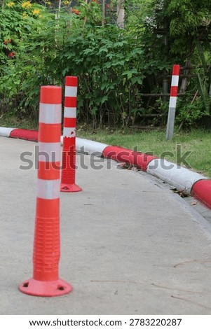 Brightly colored traffic cones and posts are placed along a road's edge to delineate boundaries and direct vehicles