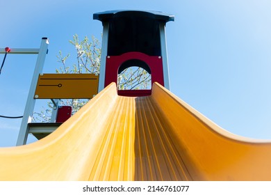 Brightly colored yellow playset with a slide and climbing frame in a playground for children who play