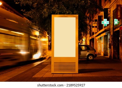 brightly lit advertising panel at tram stop on urban street. night scene. glass and metal structure. poster ad display. light box. banner and copy space. streetscape. mockup base. motion blurred tram