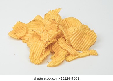 Brightly lit, golden-yellow potato chips scattered on a flat surface, with visible ridges and soft shadows