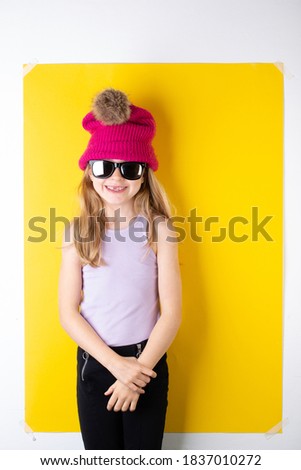 Brightly lit studio photo of a cheerful 8 year old girl framed on a yellow background.