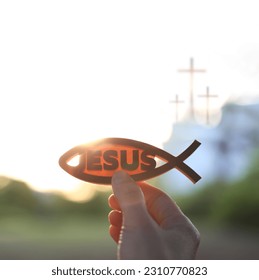 The brightly rising sunrise and the Christian symbols fish figures Ichthys and Jesus and the church cross
 - Shutterstock ID 2310770823