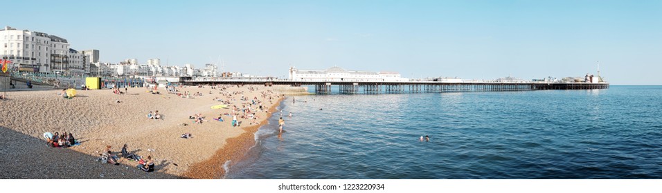 BRIGHTON, ENGLAND - JULY 9, 2018: Panoramic view of Brighton Pier from the west on Brighton beach, Brighton, UK. The pier opened in 1899 is a Grade II heritage listed structure in UK.