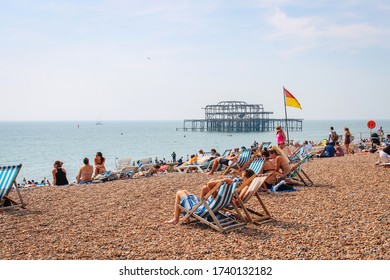 Brighton / UK - August 29 2017: People sitting on deckchairs on Brighton beach on a sunny summers day