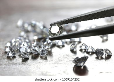 brilliant cut diamond held by tweezers - Shutterstock ID 1069154252