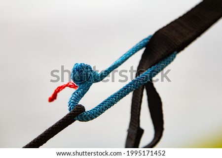 brilliant knot soft shackle woven of blue nylon or polyester rope on nature background. lighter than a carabiner. Tourist equipment
