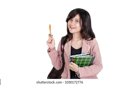 Brilliant smiling Asian female student holding a pen pointing up, isolated on white background