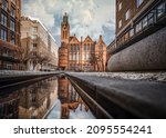 Brindley Place red brick church building reflected in water. West Midlands landmark buildings redevelopment in historic city centre reflection in stream. Birds and clouds in sky.