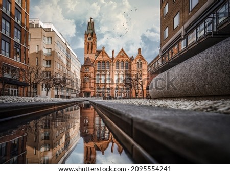 Brindley Place red brick church building reflected in water. West Midlands landmark buildings redevelopment in historic city centre reflection in stream. Birds and clouds in sky.