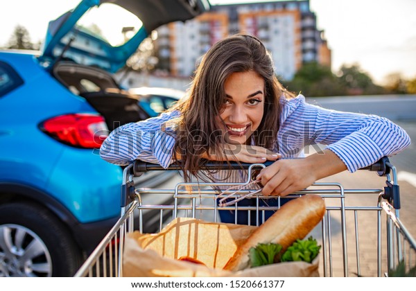 Bringing in the\
Shopping. Happy girl with groceries. Beautiful young woman shopping\
in a grocery store/supermarket. Grocery shopping done! Woman after\
shopping on parking\
lot