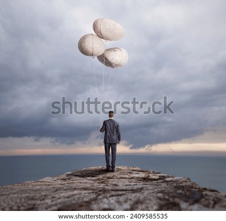 At the brink of a cliff, a visionary businessman stands facing the unknown, holding three floating rocks instead of traditional balloons. 